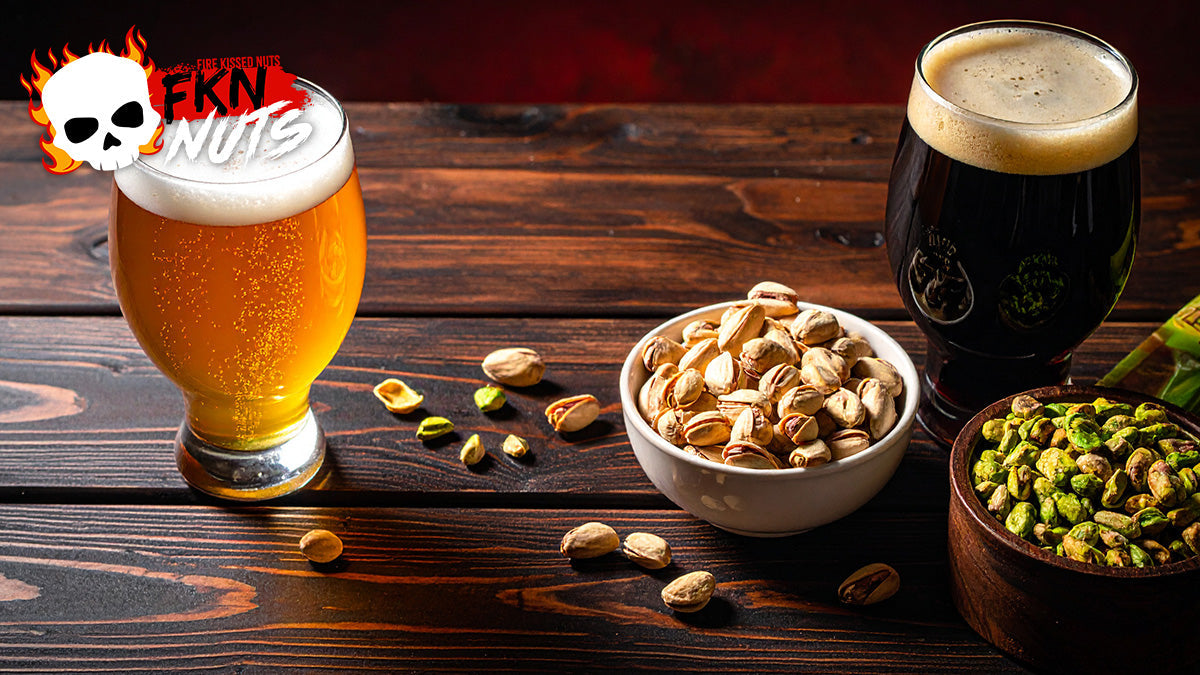 FKN Nuts spicy pistachio bags beside two craft beer glasses on a dark bar top with warm amber lighting